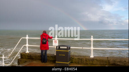 Bridlington, England, 10 Août : dame en rouge sur un arc-en-ciel tandis que le temps orageux batters le littoral : 10 août 2014 Banque D'Images