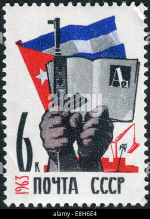 Timbre-poste imprimé en URSS, consacré à l'Cuban-Soviet amitié, montre des mains avec des armes à feu et livre, d'un drapeau Banque D'Images