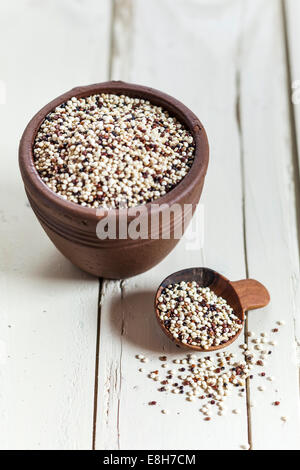 En faïence et cuillère en bois de quinoa biologique, Chenopodium quinoa, sur bois blanc Banque D'Images