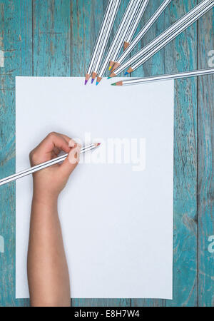 La main de l'enfant avec des crayons de couleur et feuille de papier vierge Banque D'Images