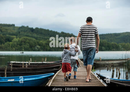 Allemagne, Rhénanie-Palatinat, Laacher See, père marcher avec deux fils on jetty Banque D'Images