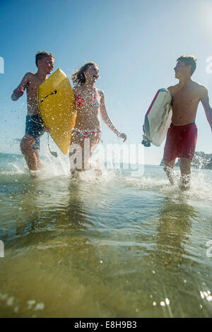 Trois adolescents avec des planches de bord à la mer Banque D'Images