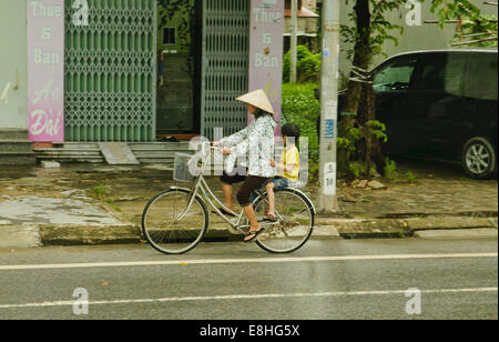 Mère et fils à cheval sur un vélo à Hanoi, Vietnam Banque D'Images