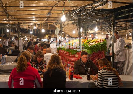 Vue horizontale de touristes de manger des aliments sur les étals de la Place Jemaa el Fna (Place Djemaa el Fna à Marrakech la nuit. Banque D'Images