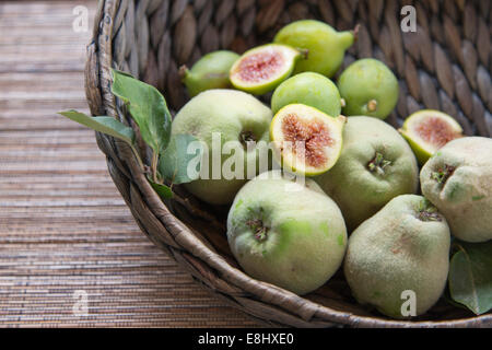 Coings et figues, panier tressé avec des figues coupées en haut Banque D'Images