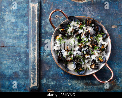 Les moules et sauce au bleu Dor dans un plat de cuisson en cuivre sur fond bleu Banque D'Images