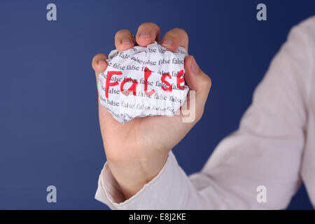 Boule de papier froissé avec les mots 'False' dans la main de femme. Banque D'Images