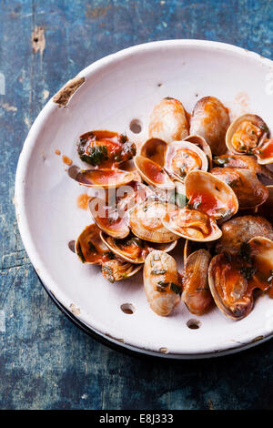 Coquillages de persil et vongole sauce de tomate dans une passoire en céramique vintage sur fond bleu Banque D'Images