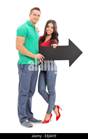 Portrait of a young couple holding une flèche vers la droite isolé sur fond blanc Banque D'Images