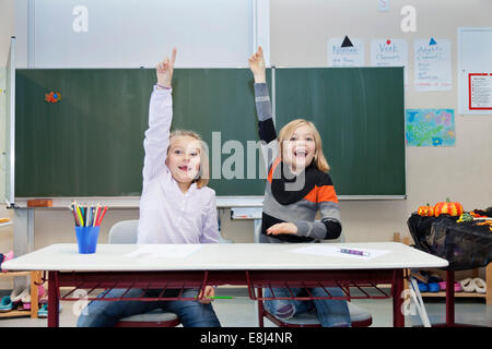 Deux écolières, 7 et 9 ans, de mettre en place leurs mains dans la classe Banque D'Images