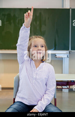 Lycéenne, 7 ans, de mettre en place ses mains dans la salle de classe Banque D'Images