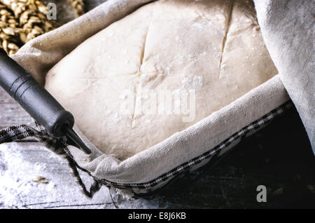 La cuisson du pain. Close up composé de pâte dans le panier d'épreuvage sur table en bois avec de la farine et les épis de blé. Voir la série Banque D'Images