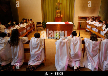 Enfants prier après avoir reçu leur première communion dans l'église catholique Saint Jacques Banque D'Images