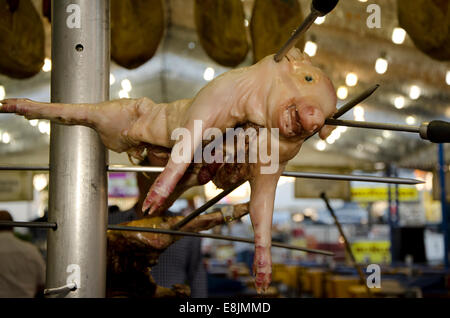 Cochon de lait, porcelet cochinillo suspendu au-dessus des tiges au grill à une fête foraine annuelle espagnol, feria, Fuengirola. Banque D'Images