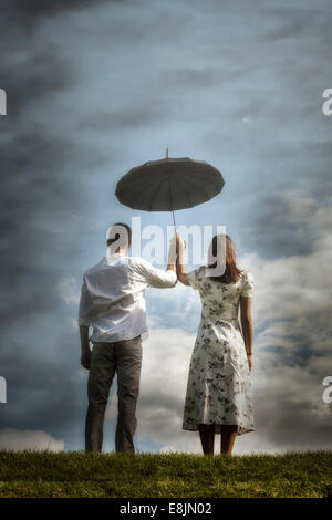 Un couple sur une prairie avec un parapluie Banque D'Images