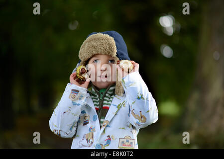 Jeune garçon enfant collectant des conkers de l'arbre de châtaigne de cheval en automne Royaume-Uni crédit: David Bagnall Banque D'Images