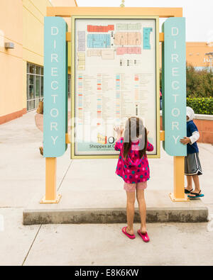 Une petite fille étudie les mots sur un magasin directeur à l'Outlet Shoppes at Oklahoma City. New York, USA. Banque D'Images