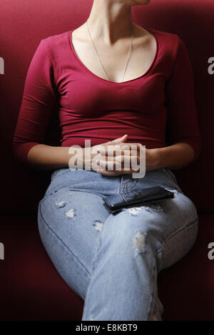 Teenage girl sitting on sofa with tablet computer dans une couverture Banque D'Images