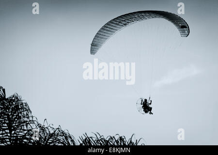 Un pilote en vol parapente propulsé avec un bleu ciel propre à l'arrière-plan Banque D'Images