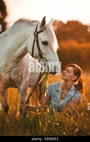 Femme avec Welsh Pony, White Horse, cheval hongre, sur prairie de la lumière du soir Banque D'Images