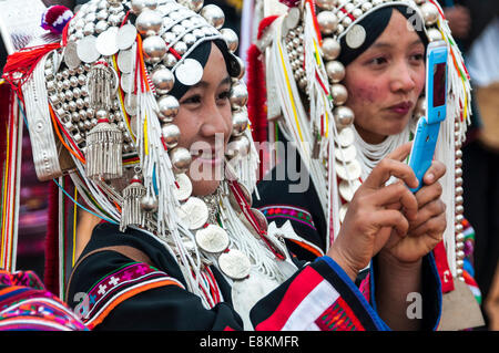 Souriante jeune femme vêtements traditionnels de la tribu Akha, hill, minorité ethnique, de prendre une photo avec un mobile Banque D'Images