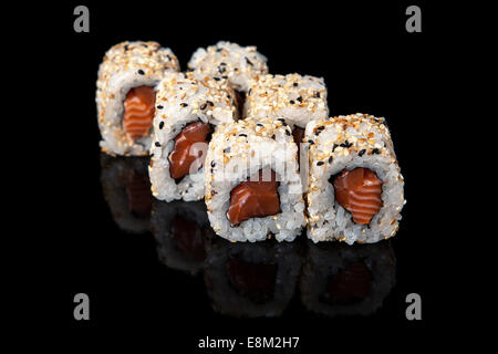 Ensemble de rouleaux de sushi avec du saumon sur fond noir Banque D'Images