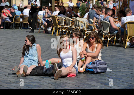 Un petit groupe de jeunes adolescents dans les vêtements d'été assis sur le trottoir de la place de la Vieille Ville, Prague, République tchèque. Banque D'Images