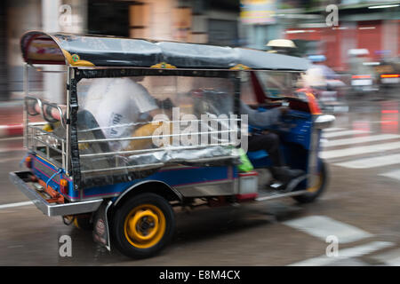 Tuk-tuk dans blurred motion durs grâce à une rue de Chinatown des pluies, Bangkok, Thaïlande. Banque D'Images