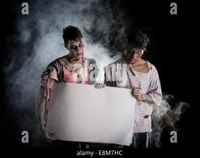 Deux hommes zombies holding empty bannière blanche, copie grand-espace pour l'Halloween Banque D'Images