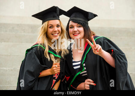 Deux heureux étudiantes dans les robes traditionnelles et de mortier sur les conseils de son diplôme diplômes Université d'Aberystwyth, Pays de Galles, Royaume-Uni Banque D'Images