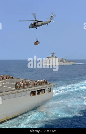 Mer de Chine orientale, le 19 mars 2014 - Un MH-60S Sea Hawk, transferts en hélicoptère des approvisionnements de la commande de transport maritime militaire une cargaison sèche Banque D'Images