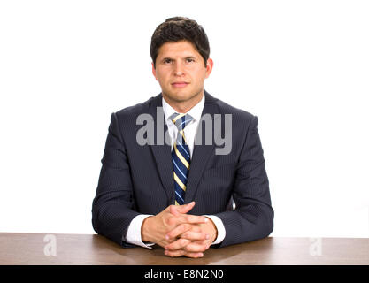 Jeune homme portant un costume pin stripe est assis à une table avec ses mains, entremêle. Banque D'Images