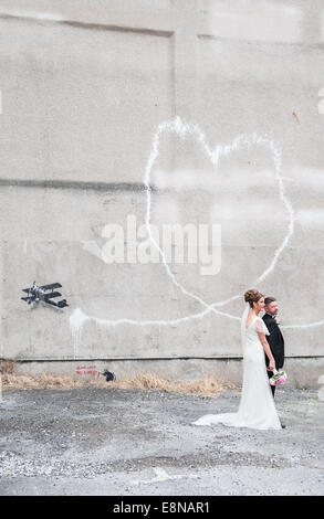 Jour de mariage Photos/Photos d'un couple en face d'une traînée de vapeur en forme de coeur -venant d'un bi-plan. Banksy,graffiti art,Amour,avion,Liverpool, Banque D'Images