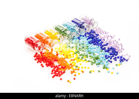 Petites bouteilles en verre rempli d'un arc-en-ciel de couleurs, de perles de tomber sur un fond blanc Banque D'Images