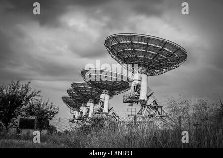 Télescope radio satellite dish baie dans un champ d'orge avant une tempête en noir et blanc Banque D'Images