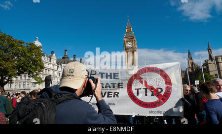 La place du parlement, Londres UK. 11 octobre 2014. Un photographe prend une photo d'une banderole sur la place du Parlement TTIP sur un jour d'action de protestation. Le partenariat transatlantique de commerce et d'investissement mettrait en œuvre un accord de libre-échange entre les Etats-Unis et l'Europe qui menacerait les droits démocratiques de la société, en particulier le Service national de santé. Kathy deWitt/Alamy Live News Banque D'Images