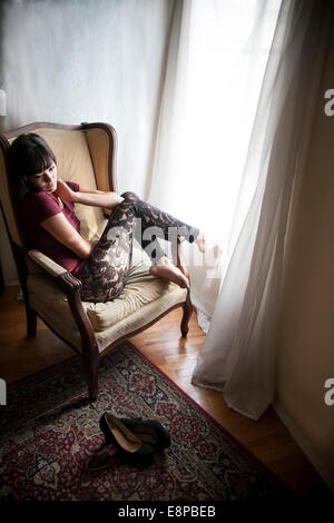 Portrait of young woman sitting in armchair Banque D'Images