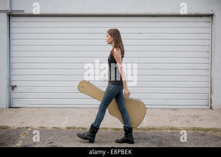 Young woman walking with guitar case Banque D'Images