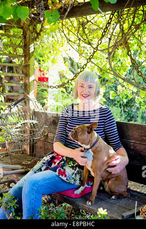 Senior woman sitting on bench with dog Banque D'Images