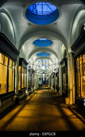 Long passage couvert de navigation dans le Royal Opera Arcade, Her Majesty's Theatre, Londres, Angleterre la nuit. Pas de personne, éclairage des magasins allumé. Banque D'Images