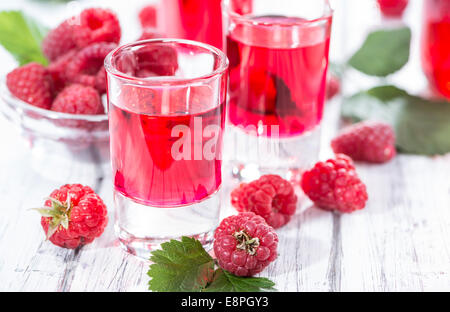 Liqueur de framboise fait maison dans un verre avec quelques fruits frais Banque D'Images