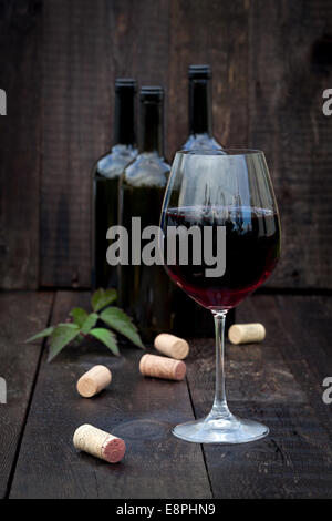 Verre de vin rouge avec des bouchons sur la vieille table en bois Banque D'Images