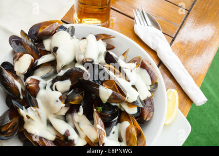 Assiette pleine de moules avec une sauce à l'ail sur table in restaurant Banque D'Images