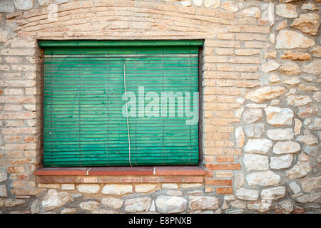 Vieille façade en pierre avec des volets en vert dans la fenêtre. La texture d'arrière-plan Banque D'Images