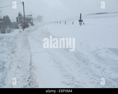 Route bloquée par la neige après une tempête de neige. Amoncellements de chaque côté de la voie. Dans Rainow près de Macclesfield, Cheshire. Les amoncellements de neige couvrir la lane Banque D'Images