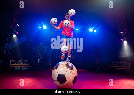 Zhora Oganisyan, le jongleur de football du cirque d'Etat de Moscou, les tentatives d'équilibre sur un géant tout en jonglant avec des ballons de football 3 avec sa main en même temps et d'essayer de "suivre" une pichenette par football supplémentaires d'un pied sur l'autre, à l'Alexandra Palace comprend : Zhora Oganisyan Où : London, Royaume-Uni Quand : 10 Avr 2014 Banque D'Images