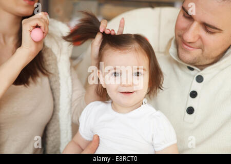 Les parents se peigner les cheveux de bébé ils Banque D'Images