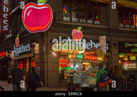 Un vendeur de hot-dog partage un coin avec un Times Square de la direction générale de la chaîne de restaurants Applebee's Banque D'Images