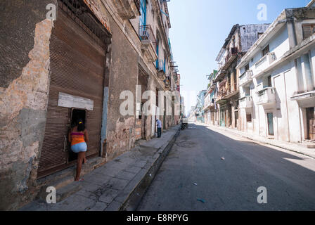 Une femme parle à un(e) ami(e) à travers une porte ouverte dans un quartier de La Havane. Banque D'Images