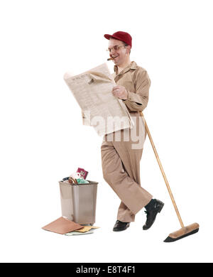 1970 ENTRETIEN NETTOYEUR BALAI MAN LEANING ON WALL STREET JOURNAL LECTURE SMOKING CIGAR SMILING WEARING RED CAP Banque D'Images